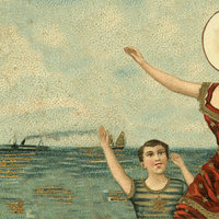 In the Aeroplane over the Sea woman at the beach pointing ahead with her head replaced by a blank circle