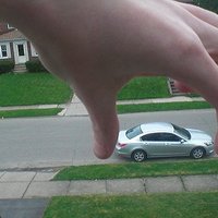 Huge hand reaching to grab a small car