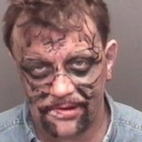 mugshot of a man with black marks all over his face