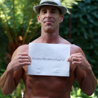 shirtless man holding a piece of paper with the writing scooby1961