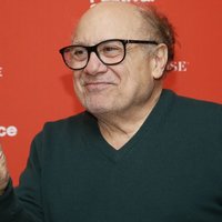 Danny DeVito throwing up a peace sign.