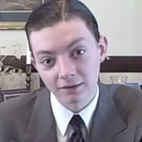 TheReportOfTheWeek / Reviewbrah during a stream while wearing a suit and tie.