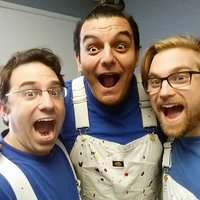 three men in blue shirts and white overalls posing together with their mouths open in surprise