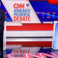 Vice President Joe Biden and Senator Bernie Sanders on stage at the CNN Democratic Presidential debate. Behind them are blue podiums and CNN logos. 