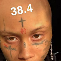 bald person with a cross tattooed on their forehead and several other facial tattoos and the number 38.4 written across their head