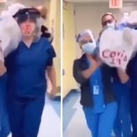 group of people in scrubs and face masks carrying a dead body wrapped in a sheet on their shoulders