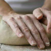pair of hands rolling a lump of dough with a miserable face of a cat's photoshopped on it