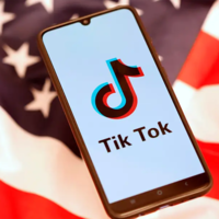 phone with the TikTok app open in front of the US flag