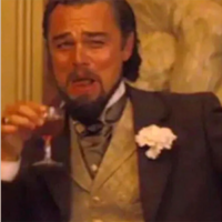 Leonardo DiCaprio in the movie Django Unchained laughing while holding a glass of liquor