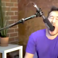 Streamer using a mic while holding it inside his mouth.
