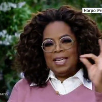 screenshot of Oprah during the meghan and harry interview with her arm up and her hands making an ok symbol by touching her index finger to her thumb. 