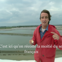 A Frenchman in a red jacket standing on a salt flat says that half of French salt is harvested there. 