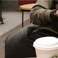 A photograph of a coffee cup, a straw, and a man's hands holding a phone -- an archetypical example of a relationship soft launch.