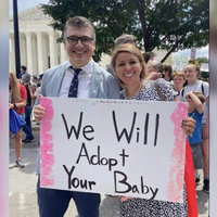 We will adopt your baby meme depicting a couple protesting at the supreme court holding a pro-life sign.