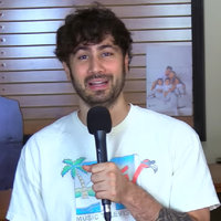 YouTuber Def Noodles, Dennis Feitosa, holding a microphone on camera.