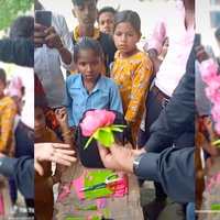young school girl stares intently as a man shows how to make a lotus flower from coloured paper