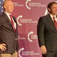 DeSantis Stance Desantis stance meme format depicting the florida governor standing in front of a turning point usa backdrop for a photoshoot at an event.