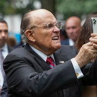 A photo of Rudy Giuliani at the 9/11 memorial attempting to take a picture with his phone.