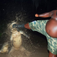 Alligator Kick / Black Guy Kicking Alligator Alligator Kick meme depicting a large black man in camo shorts kicking an alligator in the jaw in a dark swamp at night.
