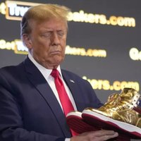 Donald Trump holding up a pair of Trump Sneakers / Never Surrender High-Tops.