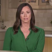 Katie Britt, wearing green, seated at a kitchen table
