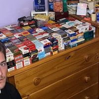 5840 Cigarettes meme depicting a photo of a man with a cig in his mouth posing with numerous boxes of cigarettes behind him.