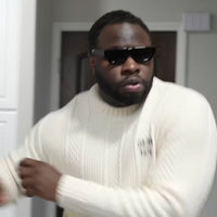 Leland Manigo dancing in sunglasses and a white sweater.