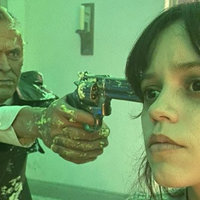 willem dafoe wax figure holding gun to jenna ortega's head