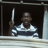 Chris from Everybody Hates Chris in a window holding a dish, ready to throw it.