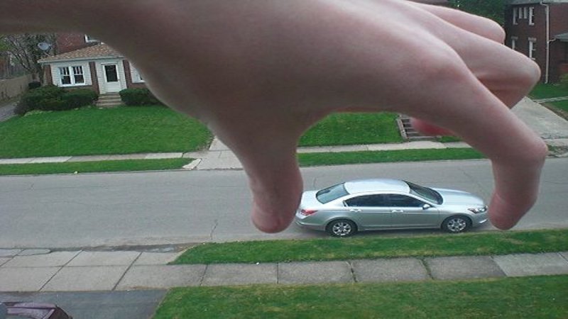 Huge hand reaching to grab a small car