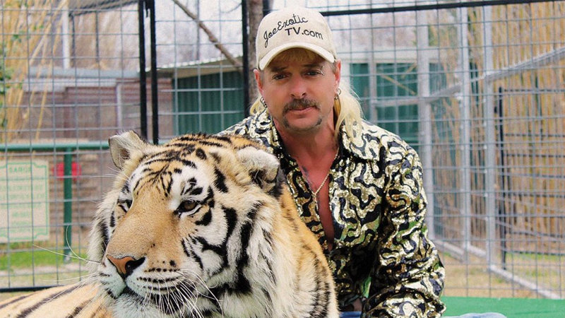 Joe exotic aka Joseph Maldonado-Passage with a hat on and next to a tiger