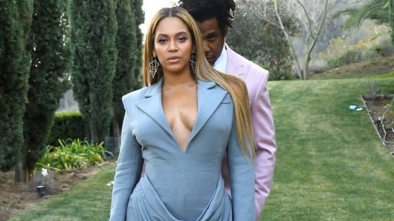 Jay Z meekly peeking over Beyonce's shoulder while she looks confidently ahead