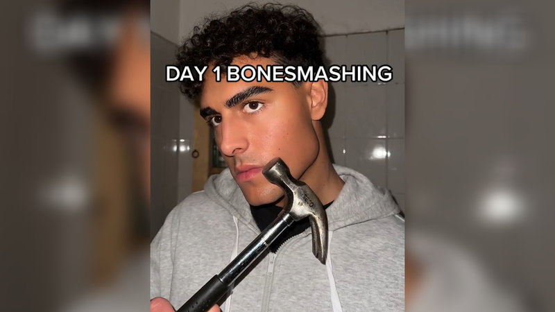 Bonesmashing / Bone Smashing trend depicting a man holding a hammer up to his face.