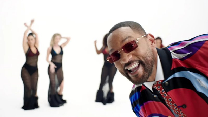 Will Smith smiling in front of four unfocused backup dancers for the Pretty Girls music video.