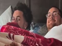 A screenshot from the father son blanket video showing a father and son in bed together