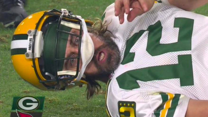 Aaron Rodgers during a Green Bay Packers game with his helmet off lying on the ground.
