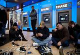People crowd into a Chase Bank ATM kiosk to charge phones and laptops at 40th Street and 3rd Avenue, one block north of where power has gone out, on October 31, 2012 in New York City. “This is the modern campfire,” one man said. (Andrew Burton/Getty Images)