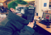bookface pose of man with green hair holding up the back cover of a Joker comic book face, perfectly lined up with his own face to give that BookFace effect