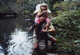 Steve holding his daughter on his shoulders and an alligator with his hands Nostalgic picture of Steve Irwin when he was much younger, holding his daughter up high on his shoulders as he uses his hand to pick up an alligator