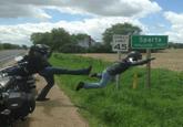 Funny picture of someone kicking a person off the shoulder of the road, with a road sign that reads SPARTA nearby.