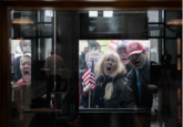 group of people with usa flags shouting through locked glass doors