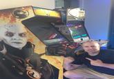 Person sitting next to a Mortal Kombat 4 arcade machine.