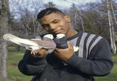 Mike Tyson holding two pigeons towards each other as if trying to make them kiss. The photograph was taken for Sports Illustrated in 1985.