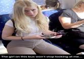 A photograph of a blonde girl sitting on a bus or train, looking up at a person taking a photo of her with an unamused expression. The meme is captioned, "The girl on this bus won't stop looking at me."