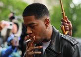 A series of images taken by Michael M. Santiago showing Kid Cudi arriving at Manhattan Federal Court to testify against Diddy began making the rounds on May 22nd, showing him dressed in a black leather jacket, blue jeans, and smoking a c--------. 
