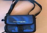 A photo of a Nintendo DS bag lying on a table. The straps curve in a way that can make it resemble a woman's backside.