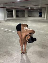 A photo of Rubi Rose bending over in a parking garage in front of her Cybertruck. The Cybertruck has been photoshopped out.