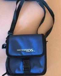 A photo of a Nintendo DS bag lying on a table. The straps curve in a way that can make it resemble a woman's backside.