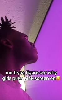 A screenshot of a TikTok captioned, "me tryna figure out why girls put a pink screen on." The TikTok shows a man staring at a pink TV screen.