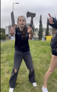 A screenshot from a video of a Scottish girl brandishing a knife and an axe. In the video, she was allegedly defending herself from attackers.